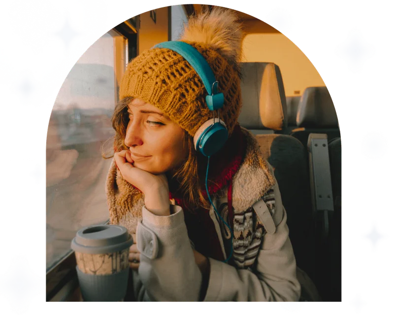 Thoughtful woman in the train looking through the window listening to headphones