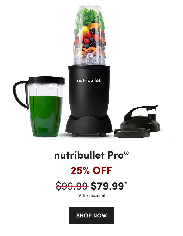 A black personal nutribullet blender with a blending cup filled with kale, berries, and almonds, alongside a handled cup of green juice and two lids.