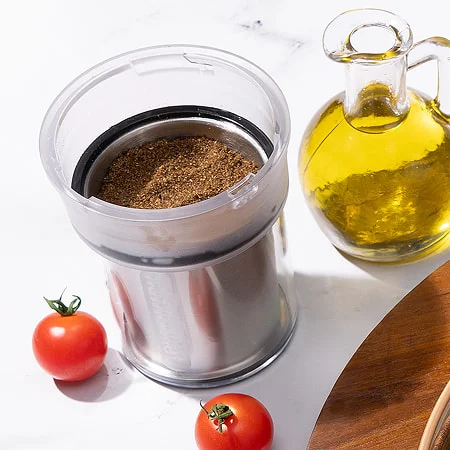 a nutribullet grinder containing za’atar spice blend beside oil and tomatoes, ideal for middle eastern dishes