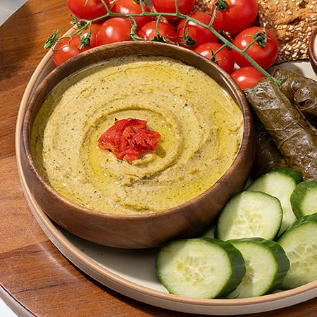 a creamy hummus bowl garnished with za’atar blend, paired with cucumber slices and pita bread