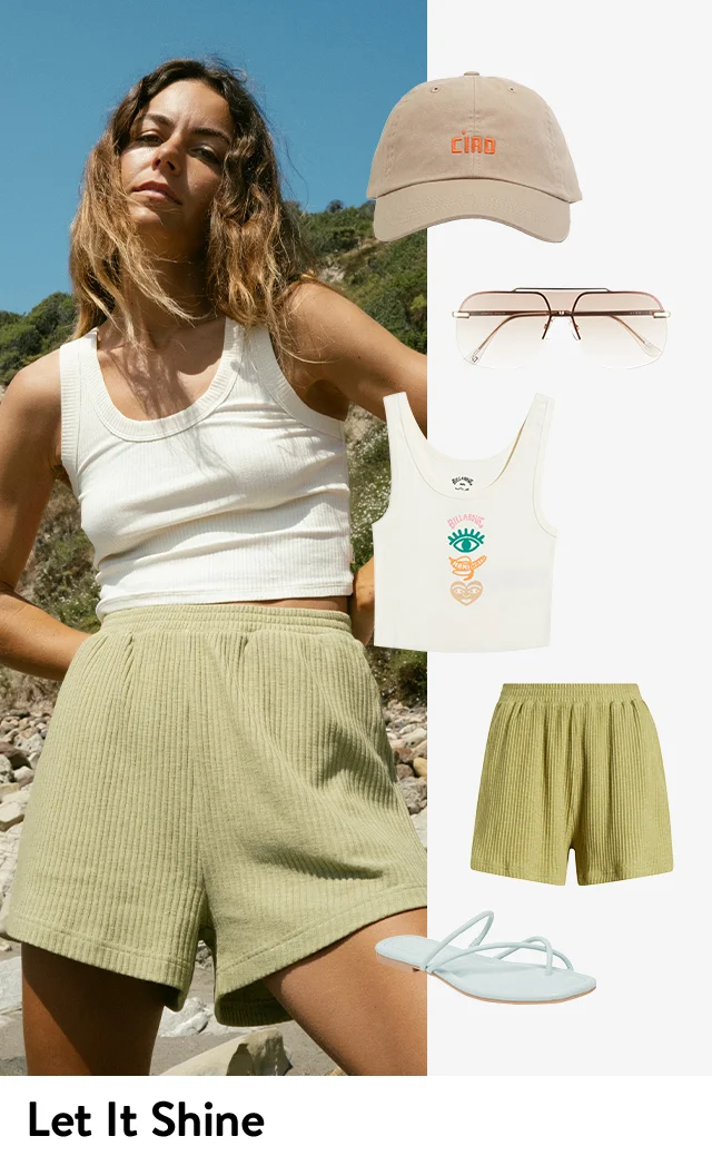 A woman wearing a cropped tank top and ribbed shorts; a Billabong graphic tank, ribbed shorts, Ciao baseball cap, sunglasses and sandals.