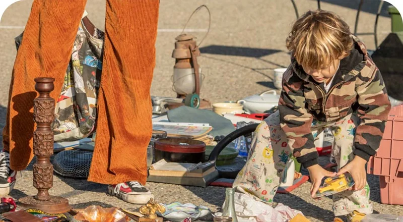 A boy and his mom browse used goods at an outdoor swap meet.