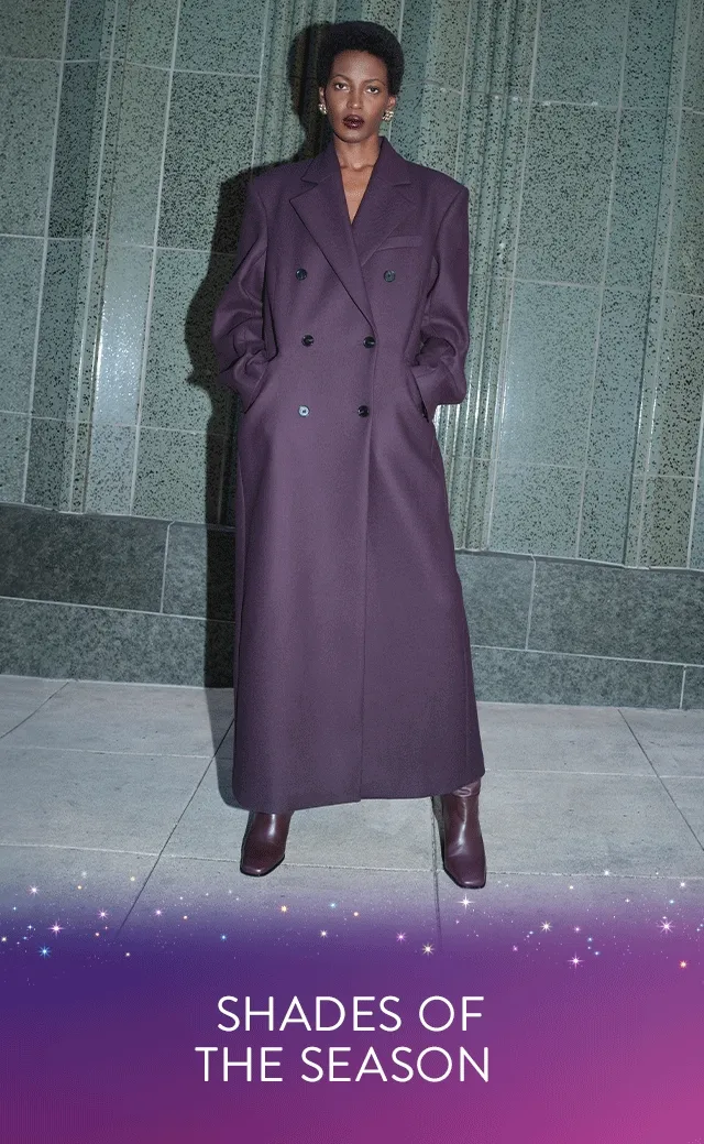 A woman wearing an oversized purple coat. A woman wearing a brown cardigan with a black skirt.