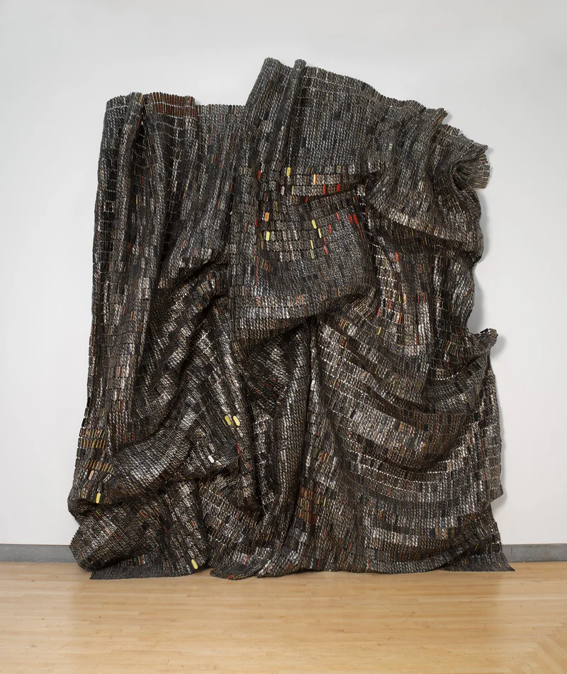 Glistening, cascading sculpture constructed with bottle tops and copper wire