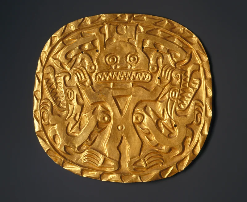 A circular gold object featuring an animal figure with large teeth