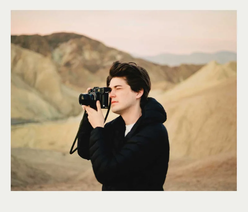 Image of a man taking a photo with a film camera in the desert.