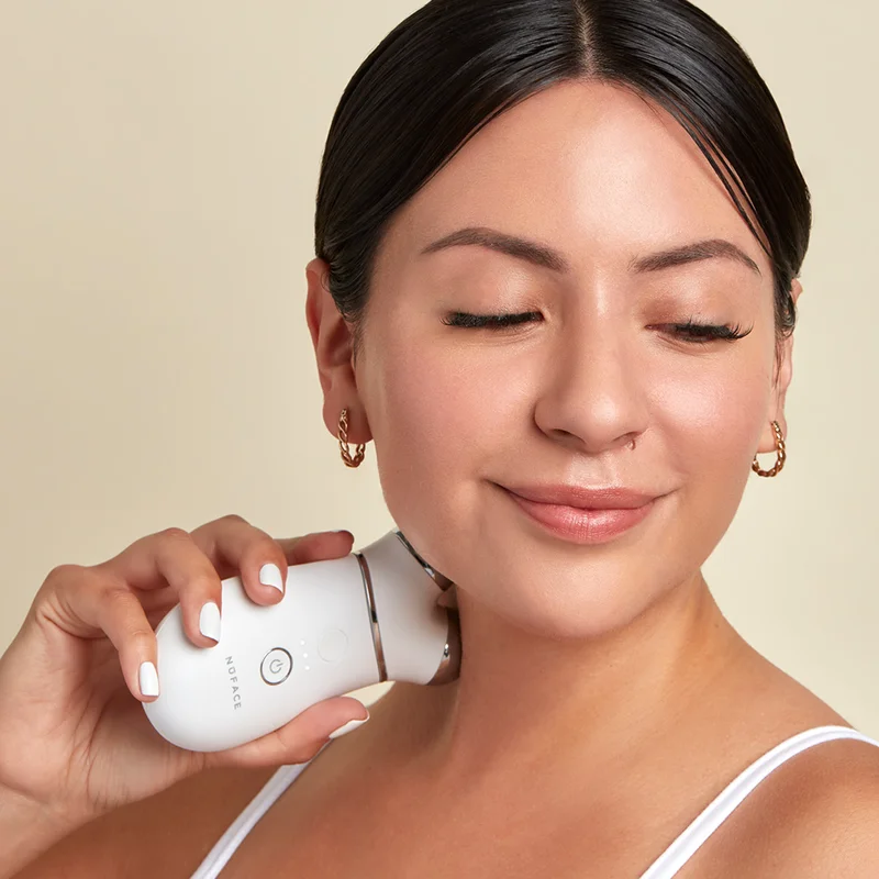 Woman holding TRINITY+ Device to her neck to achieve a lifted appearance.