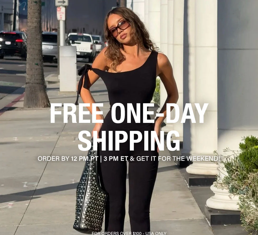 Stylish woman in black one-shoulder jumpsuit, sunglasses, and studded bag walking outdoors. Get free one-day shipping for chic weekend outfits!