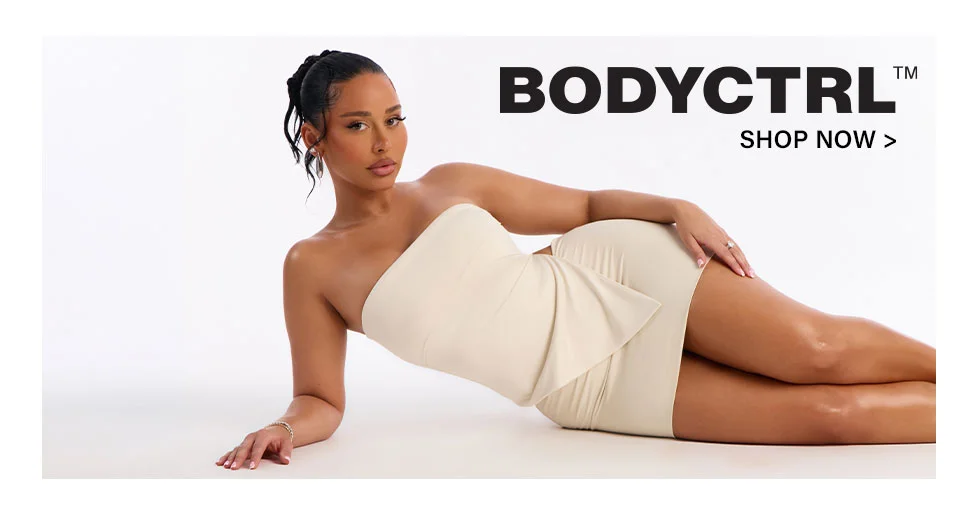 Confident woman modeling a cream strapless bodycon mini dress, reclining on white. Shop the BODYCTRL™ collection now.