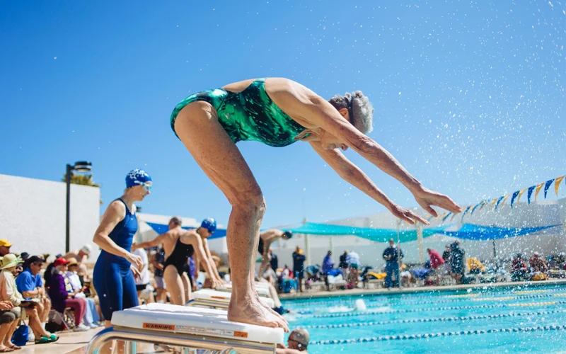 A swimmer prepares to dive into a pool during a relay in the Arizona Senior Olympics.