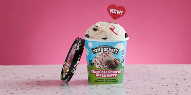 Pink background with open pint of Ben & Jerry's Chocolate Covered Strawberry ice cream. In the ice cream is a sign that reads, 'New!'
