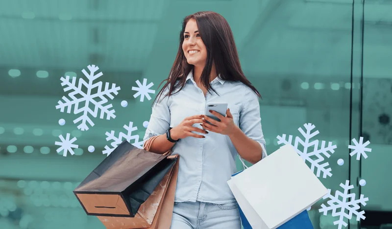 A very excited shopper smiling while holding their phone and multiple shopping bags on their arms.
