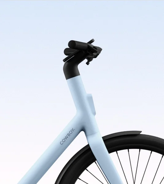 A front-facing view of the Cowboy bike in the Breeze colorway, highlighting the sleek handlebar design, integrated front light, and smart display.