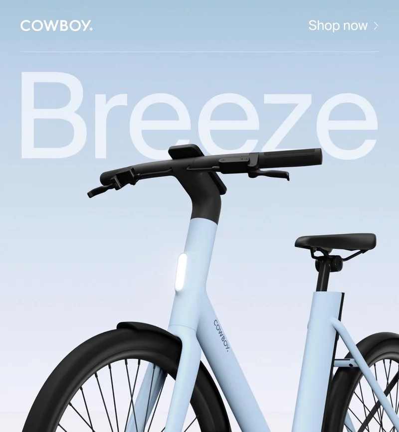 A Cowboy e-bike in the Breeze colorway, a soft blue frame with black accents, shown from a low angle against a gradient background with the word “Breeze” in large text.