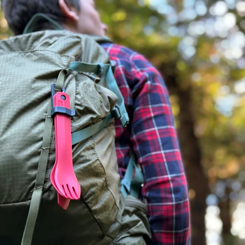 Hiker with K/F/S utensil set hanging from backpack.