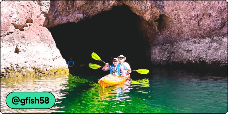 Image Description: Two people in an orange kayak coming out of a cave and paddling through clear green water. There is a tag attribution in the corner with username @gfish58.