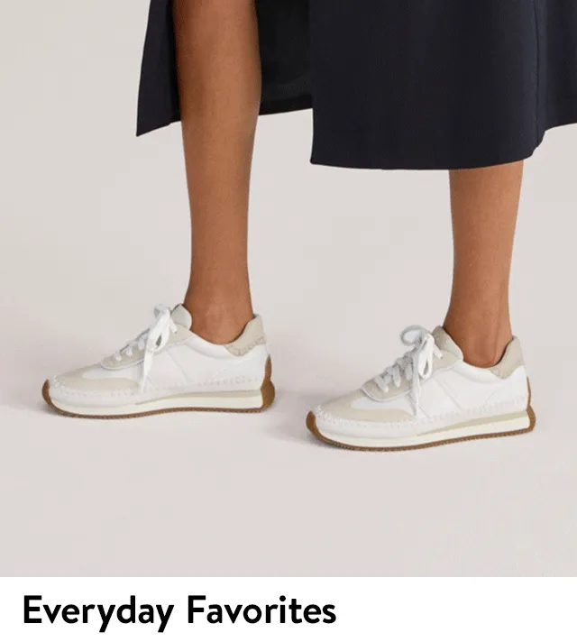 A woman wearing a dress and white sneakers.