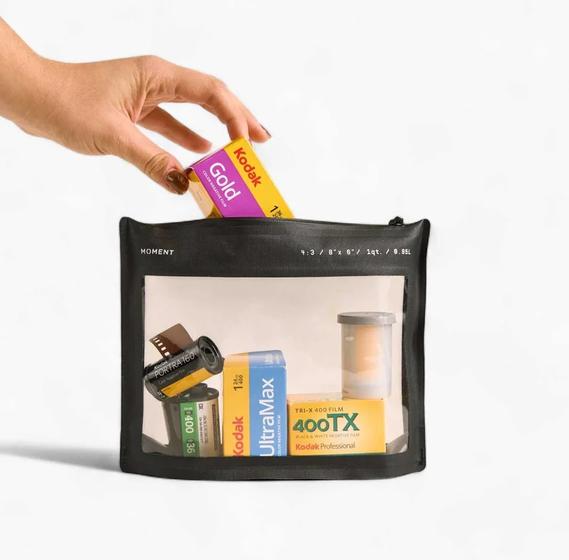 Image of a woman's hand putting a roll of film into a moment film pouch