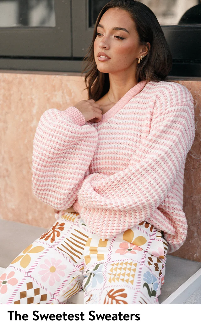 A woman wearing a pink-and-white striped crewneck sweater.