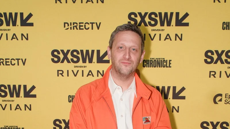 Image may contain: Tim Robinson, Person, Standing, Clothing, Footwear, Shoe, Coat, Jacket, Accessories, Belt, and Adult