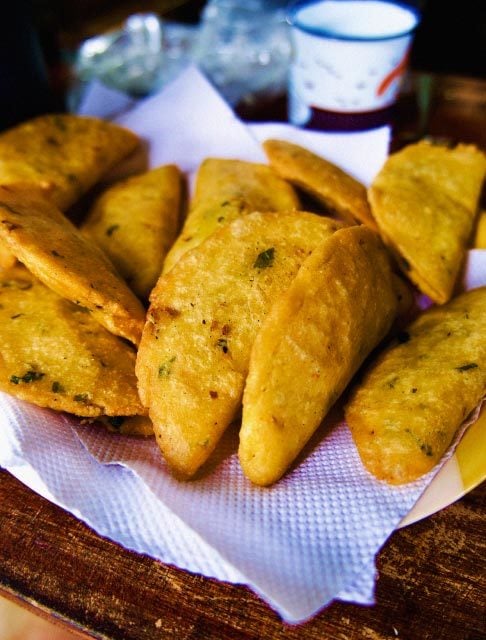 Image Description: A plate of fried empanadas on a wooden table