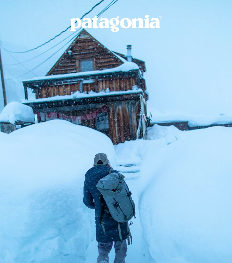 Patagonia. A person walks toward a snowbound cabin.