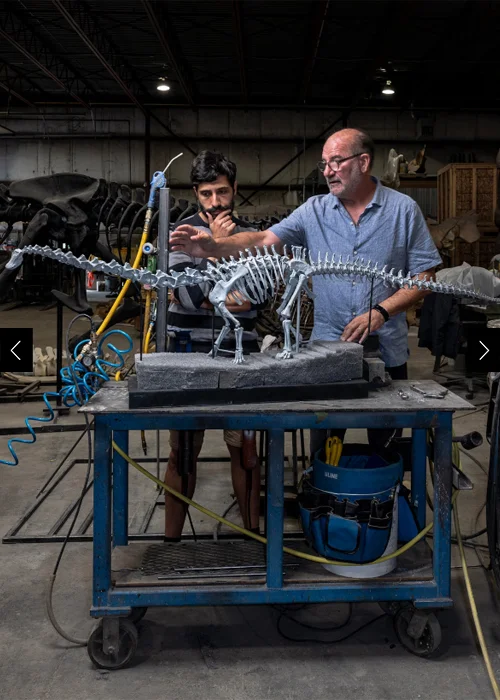 Paleontologists Luis Chiappe and Pedro Mocho study a model of a Diplodocus at Research Casting International, where real dinosaurs are reconstructed.