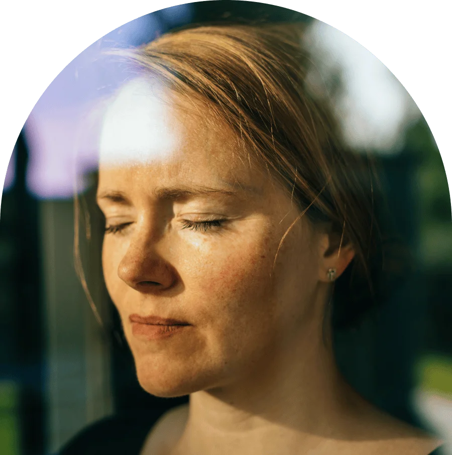 Portrait of woman with closed eyes through a window while daydreaming.