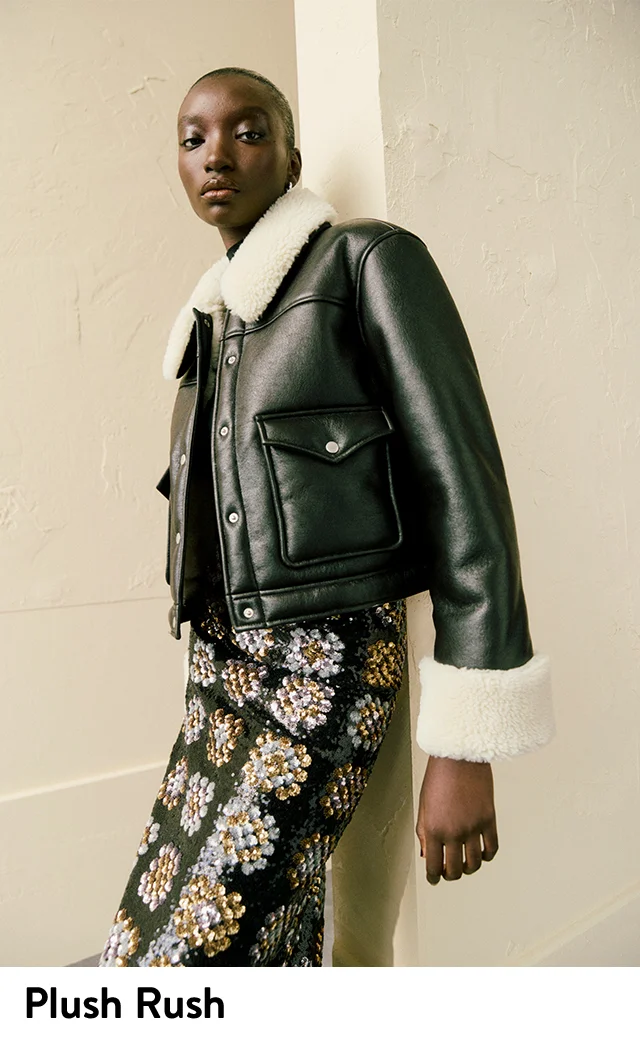 A woman wearing a black coat with faux-shearling trim.