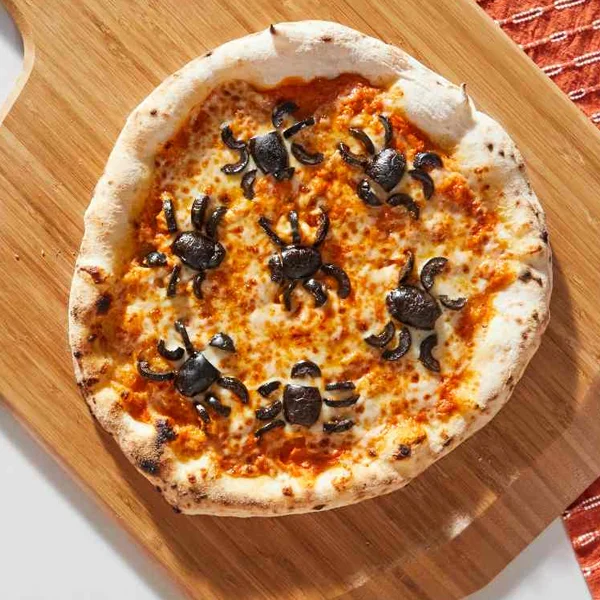A cheesy pizza topped with olives cut up to look like spiders