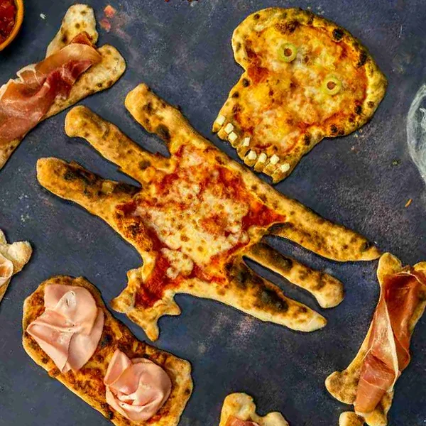 A large pizza made from different dough pieces resembling a skeleton