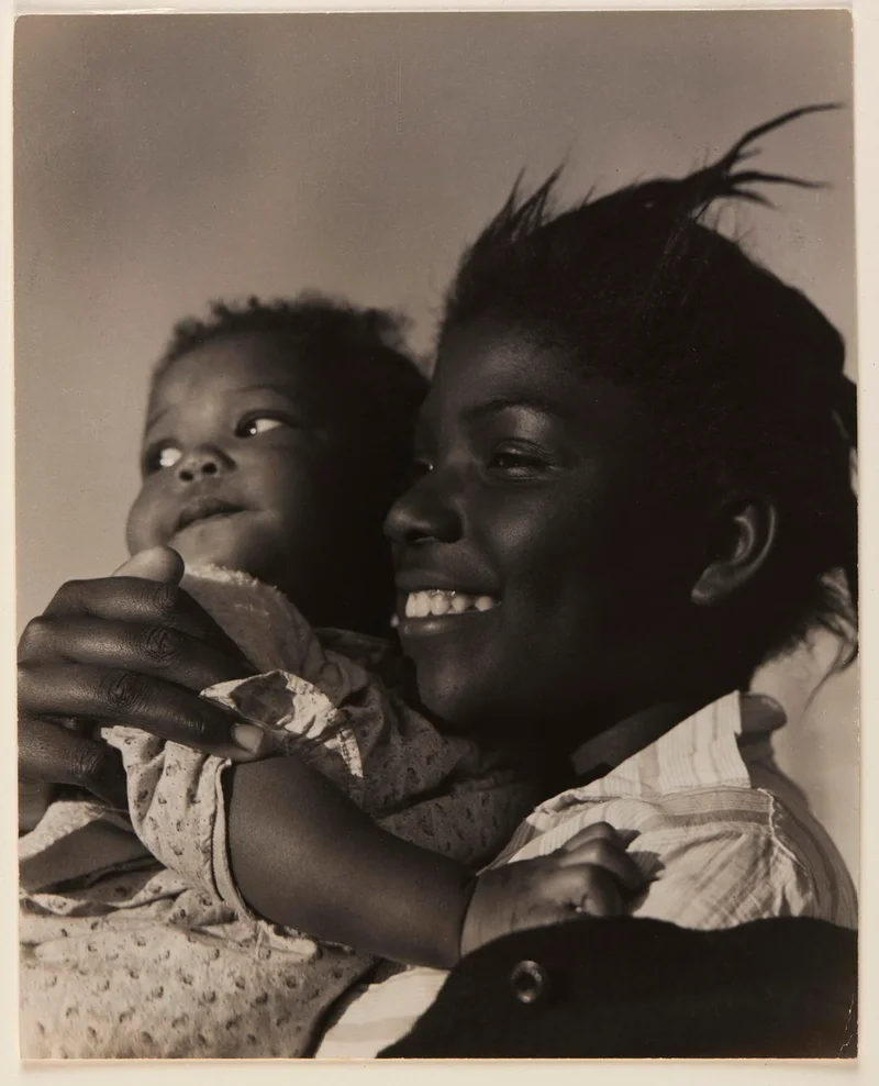 Black-and-white photograph of a woman holding a baby and smiling