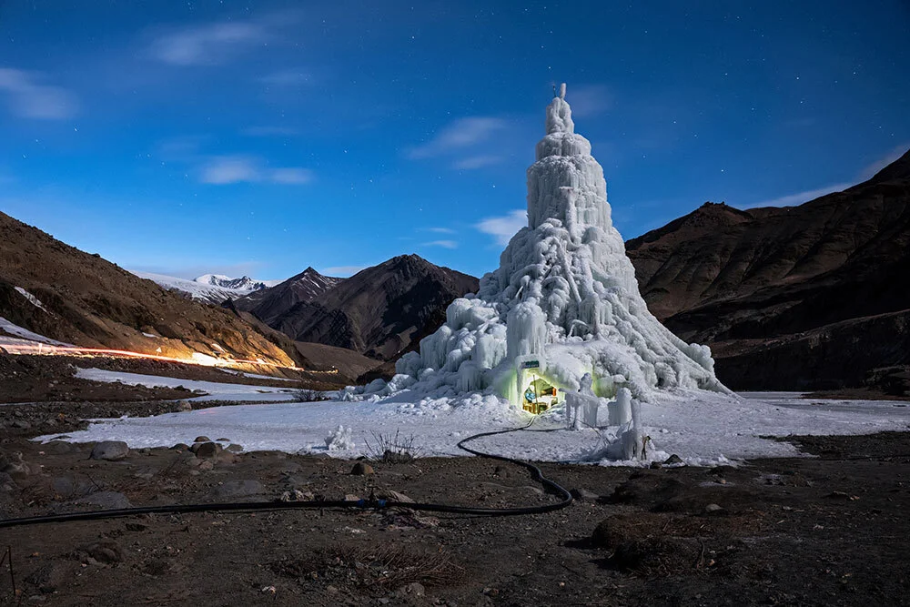 An ice stupa, or artificial ice tower, with a cafe built into its base