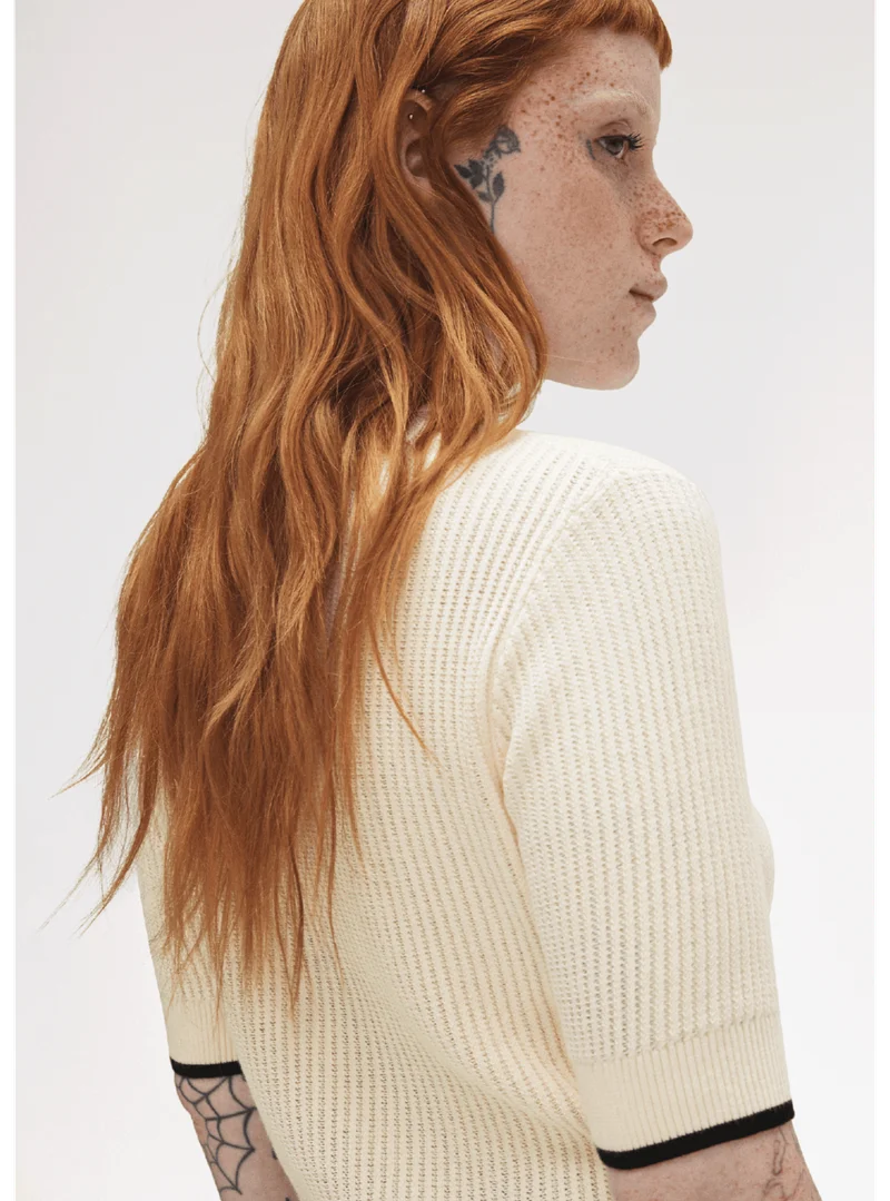 Fred Perry New Releases: Women model wears a Fred Perry Mesh Knit Polo Shirt in Silky Peach