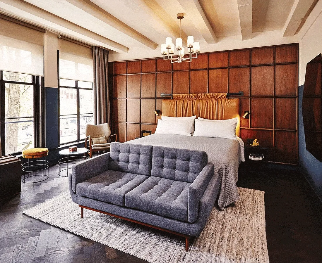 Image Description: A rotating gif of hotel rooms including a white bed with a brown leather headboard behind a blue velvet couch, a white bed with a green headboard against a green accent wall, and a white bed behind a green velvet ottoman, a sliding door reveals a freestanding bathtub.