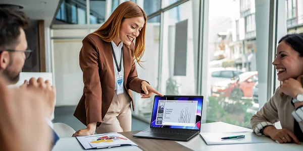 Three coworkers in a meeting room enjoying an innovative presentation on a Dell Pro 14 Premium Laptop computer.