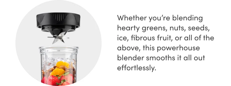 A blender with exposed metal blades hovers above an open glass jar. Inside the jar are visible ingredients such as whole strawberries, orange slices, ice cubes, and assorted nuts, ready to be blended together.