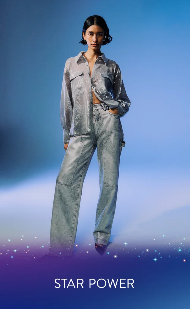 A woman wearing a shimmering button-front shirt with blue jeans.