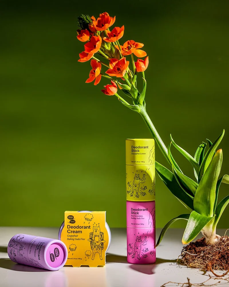 Four deodorants sit on a tabletop with a beautiful flame-red orchid