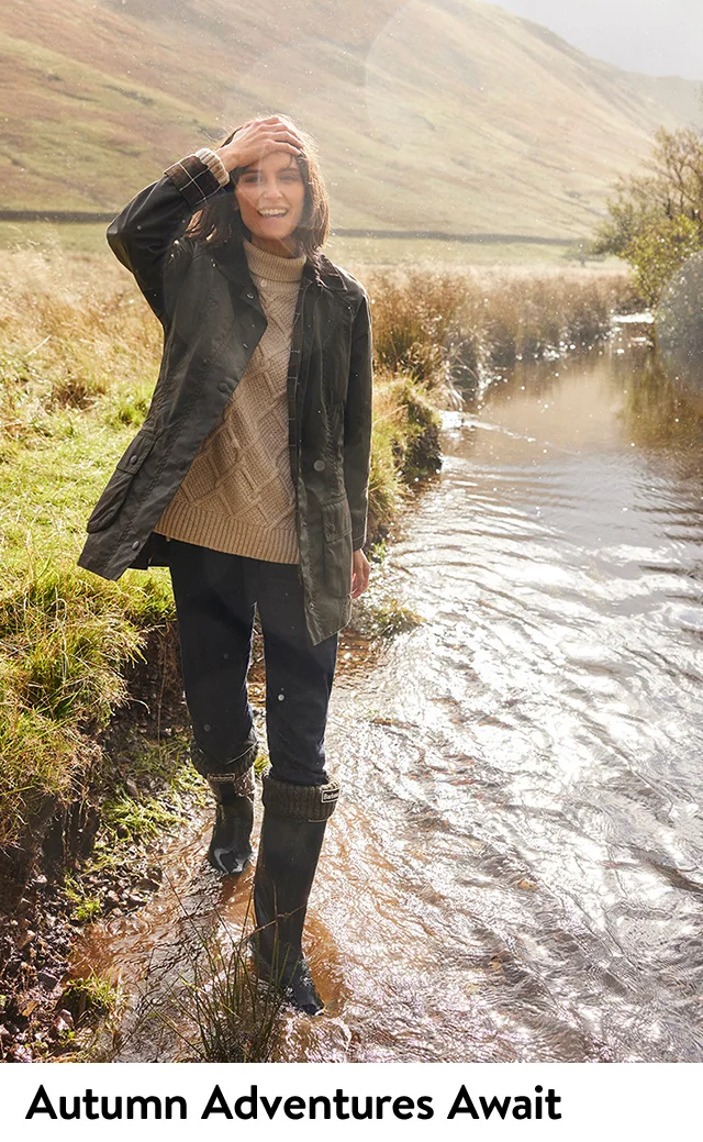 A woman wearing a jacket with a sweater, pants and rain boots.