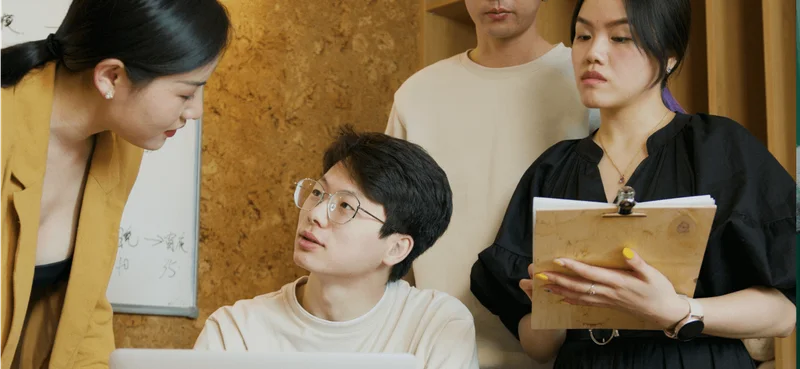A group of colleagues have a discussion around a laptop.