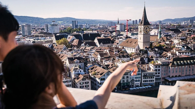 Image description: Pair of tourists viewing Old Town Zurich, from above
