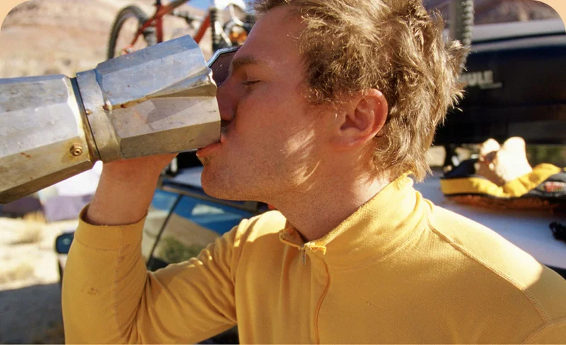 A person drinking coffee out of a coffee pot.