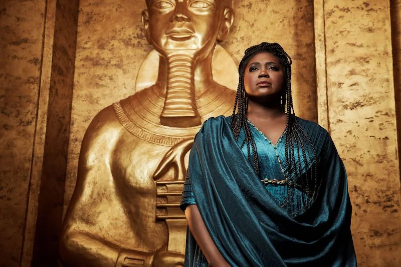 An opera singer in front of a gold backdrop