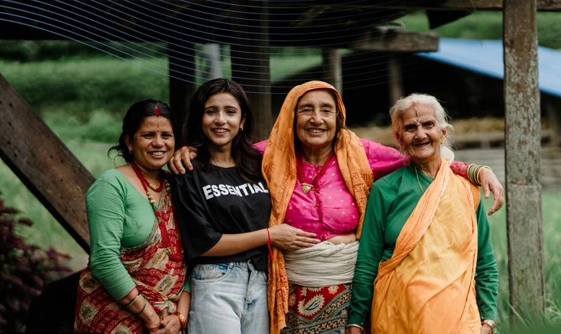Four generations of Nepalese women stand with their arms around each other
