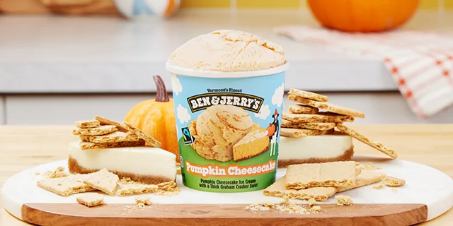 Pint of Ben & Jerry's Pumpkin Cheessecake ice cream surrounded by cheesecake and graham crackers.