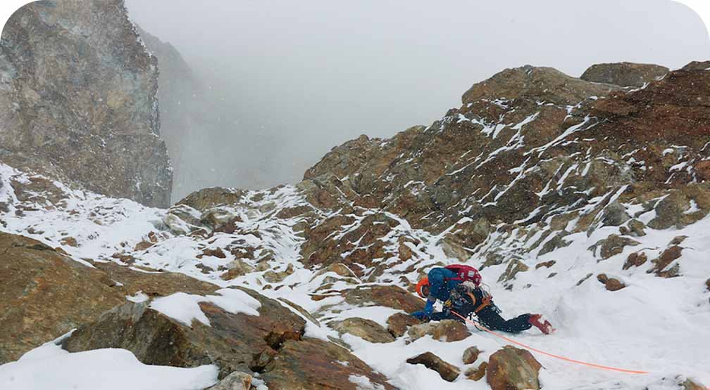 An alpine climber on a mix of rock and snow.