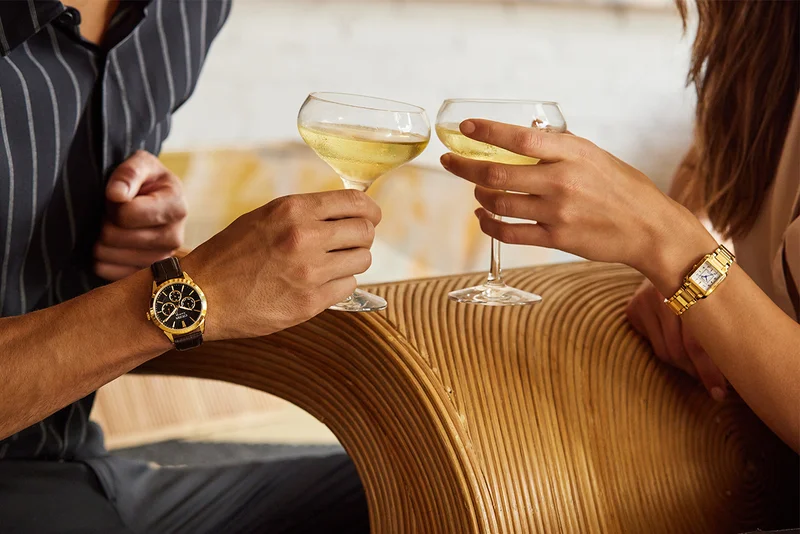 man and woman toasting drinks and wearing Rolan BU2112-06E and Citizen L BiancaEW5602-57D
