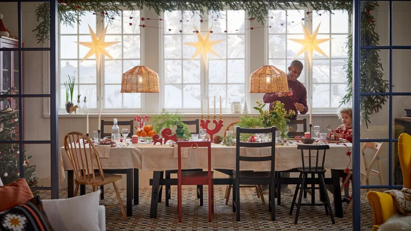 A man and child at a long table set up for a festive celebration with tableware, candles and plant decorations.