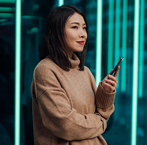 Young woman using mobile phone against futuristic holographic background